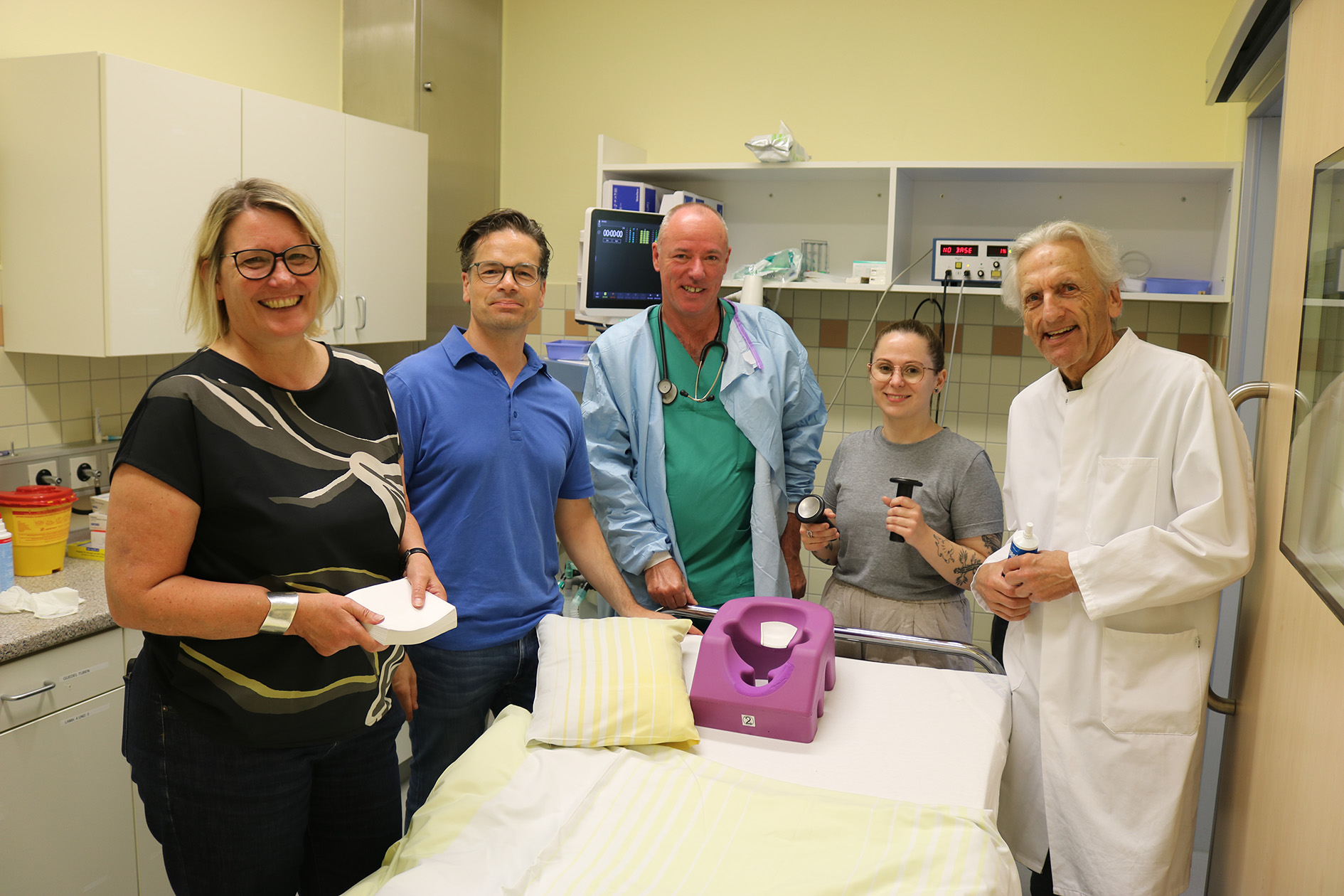 Fünf Personen stehen rund um ein Bett